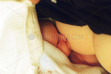 Ein neugeborenes Kind wird von seiner Mutter gestillt