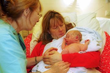 Eine Hebamme betreut Mutter und Kind nach der Geburt