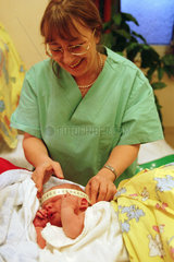 Eine Hebamme betreut ein neugeborenes Kind nach der Geburt