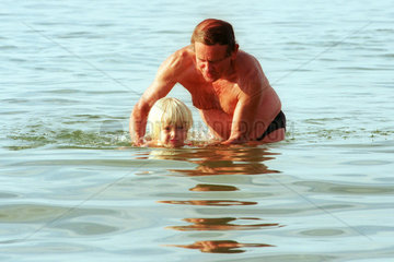 Ein Grossvater lehrt seinen Enkel schwimmen