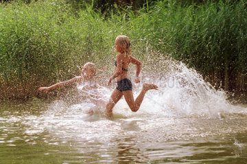 Zwei Maedchen rennen in einen See