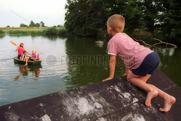 Ein Kind beobachtet ein Boot auf einem See