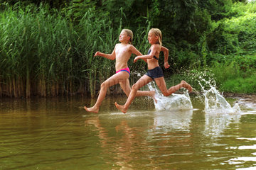 Zwei Maedchen rennen in einen See