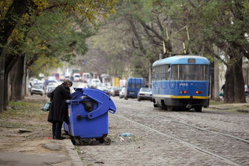 Odessa  Strassenzene  ein Mann durchwuehlt einen Muellcontainer