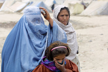 Eine Frau  verhuellt in einer Burka mit Kind.