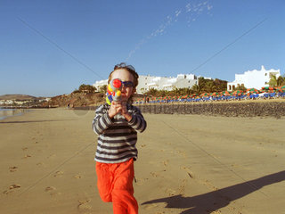 Ein Kind mit einer Spielzeugpistole am Strand