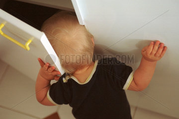 Ein neugieriges Kind steckt seinen Kopf in einen Schrank