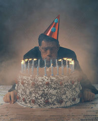 Ein Mann pustet die Kerzen seiner Geburtstagstorte aus