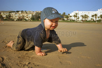 Ein Kind krabbelt am Strand