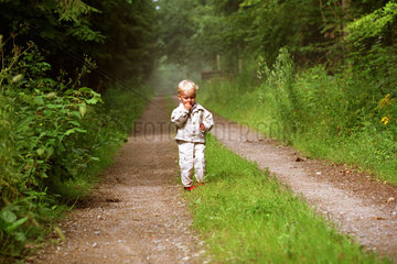 Ein einsames Kind auf einem Waldweg