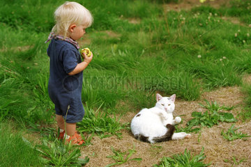 Ein Kind mit einer Katze auf einer Wiese