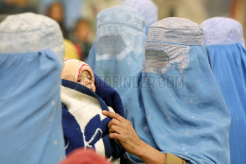 Frauen  verhuellt in Burkas mit Kleinkind.