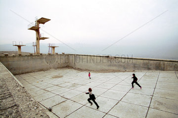 Kinderspiele im einem zerstoerten Schwimmbad  Kabul.
