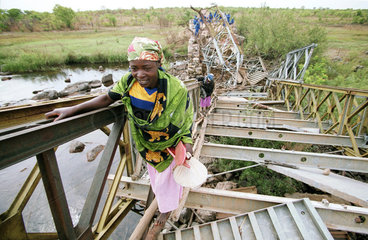 Frauen ueberqueren eine zerstoerte Bruecke  Angola.