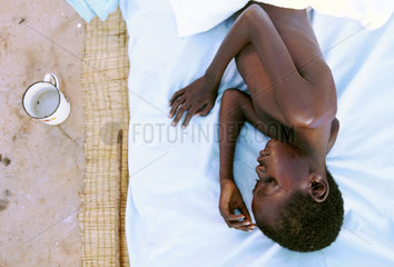 Junger Aidspatient liegt auf einer Matratze