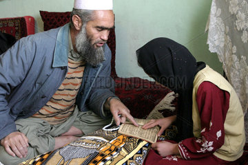 Koranschuelerin wird von einem Imam unterrichtet