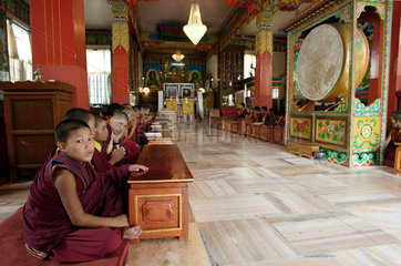Junge buddhistische Moenche in Gewaendern sitzen in einem Kloster