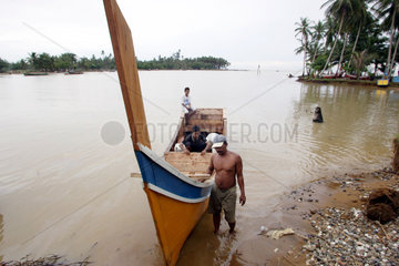 Fischer schiebt sein traditionelles Fischerboot an den Strand