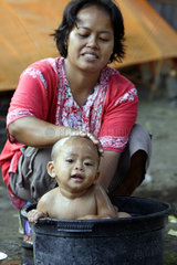 Indonesien  Java  eine Mutter waescht ihr Kleinkind in einer Plastikwanne