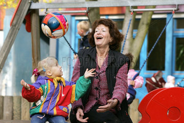 Berlin  eine Grossmutter spielt mit einem Maedchen auf einem Kinderspielplatz Ball