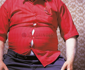 sitzender dicker Mann mit aufplatzendem rotem Hemd