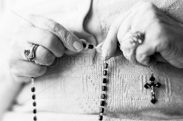 Alte Frau betet mit einem Rosnkranz