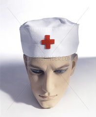 maennlicher Puppenkopf mit Muetze mit Abzeichen vom Roten Kreuz
