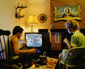 Mann und Frau sitzen zu Hause im Wohnzimmer und schauen Fernsehen