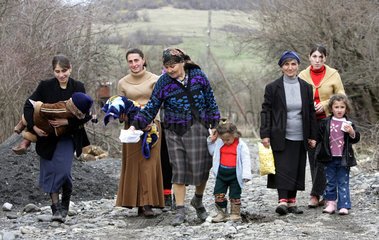 Muetter tragen ihre kranken Kinder auf einer Dorfstrasse