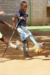 Kenia  eine Junge mit Orthese spielt Fussball in der Missionsstation Nyabondo