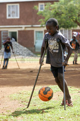 Kenia  Koerperbehinderter Junge spielt Fussball in der Missionsstation Nyabondo