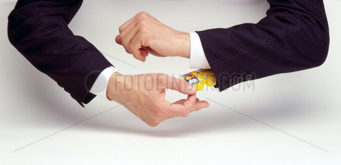 Eine Hand zieht eine Kreditkarte aus dem Aermel