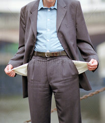 Ein Mann im Anzug zeigt seine leeren Taschen