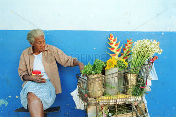 Aeltere Frau neben einem Einkaufswagen voller Pflanzen