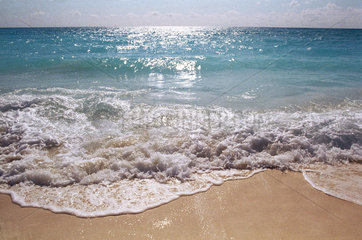 An den Strand aufschlagende Welle tuerkisblauen Meeres