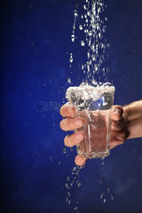 Frauenhand mit Glas faengt Wasser auf