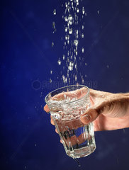 Hand mit Glas faengt Wasser auf