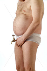 dicker Mann in weisser Unterhose haelt einen Wasserhahn vor sein Geschlecht