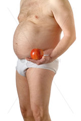 dicker Mann in weisser Unterhose haelt einen Apfel in der Hand