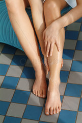 Junge Frau cremt ihre Beine ein