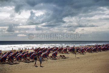 Viele Sonnenschirme am stark bewoelten Strand