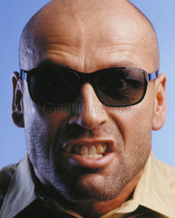 Portrait eines grimmigen Mannes mit Sonnenbrille