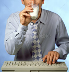 Ein Mann trinkt beim Arbeiten am Computer Milch