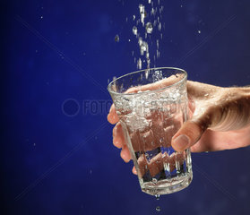 Hand mit Glas faengt Wasser auf