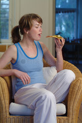 Junge Frau isst ein Stueck Pizza