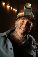 Grubenarbeiter mit Helm und Koerper voll Kohlenstaub