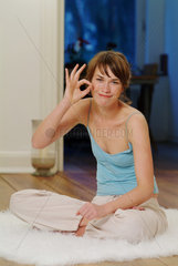 Junge Frau sitzt zu Hause und macht Yoga