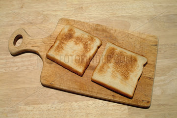 Zwei Toastscheiben liegen auf einem Holzbrett
