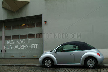 VW New Beetle parkt neben einer Ausfahrt