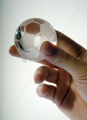 Eine Hand mit einem kleinen Fussball aus Glas